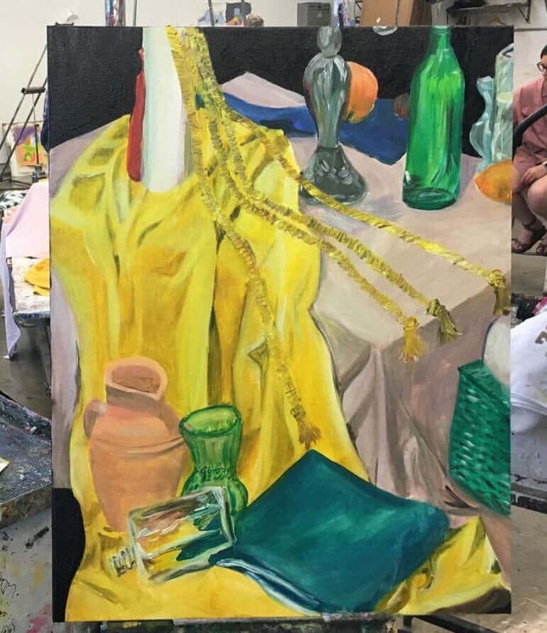 Colorful still life painting with a yellow tablecloth, bottles, and fruit